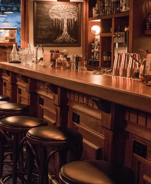 Warm wood interior of Mandinga Rum Bar in Casco Viejo, featuring a polished bar top, leather stools, and a chalkboard mural of a tree.